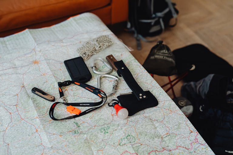 A collection of travel tools and gear laid out on a map, ready for an outdoor adventure.
