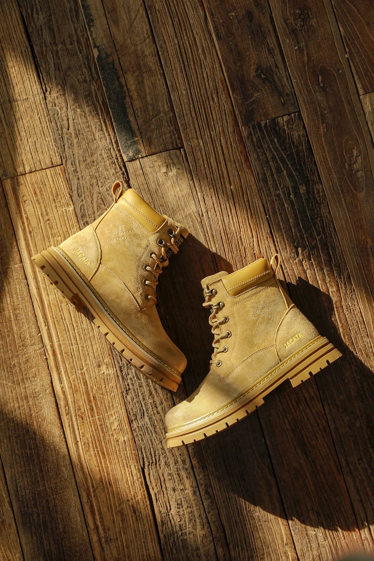 Tan work boots displayed on a rustic wooden floor, in natural lighting.